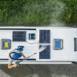 Men Pressure Washing RV Camper Van Roof Equipped with Solar Pane