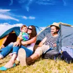 Young couple with their baby daughter in tent, summer